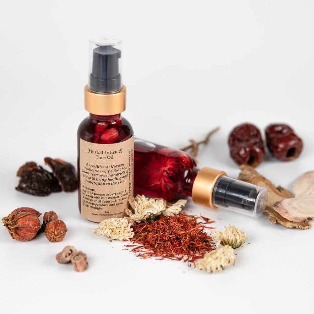 Herbal-infused face oil surrounded by dried jujube, chrysanthemum, safflower, and licorice root