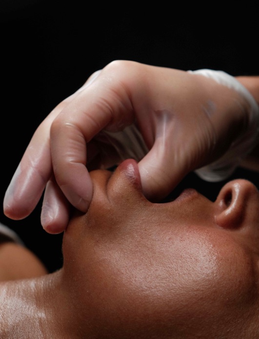 An esthetician releasing jaw tension during a sculpting facial massage at THE ONE Clinic in Austin